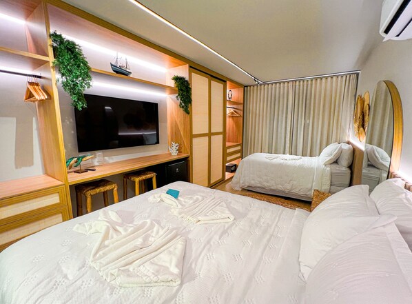A hotel room with a bed, a desk, a television, and a wardrobe.