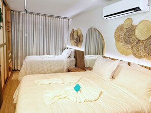 Hotellihuone, jossa on kaksi sänkyä, suuri peili ja seinälle asennettu ilmastointilaite.