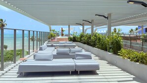 A modern outdoor lounge area with tiered seating and a view of the ocean. - Setai Yacht Luxxor - By Almare Flats (João Pessoa)