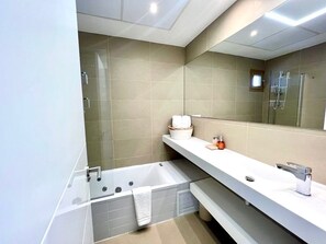 A modern bathroom with a bathtub, a large mirror, and a shower area. - Apartments in Intempo by Leo Apartments (Benidorm)