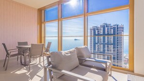 Ein modernes Wohnzimmer mit großem Fenster, einer Couch, einem Tisch und Stühlen.