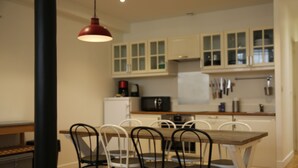 A modern kitchen with white cabinets, a dining table with chairs, and a red pendant light.