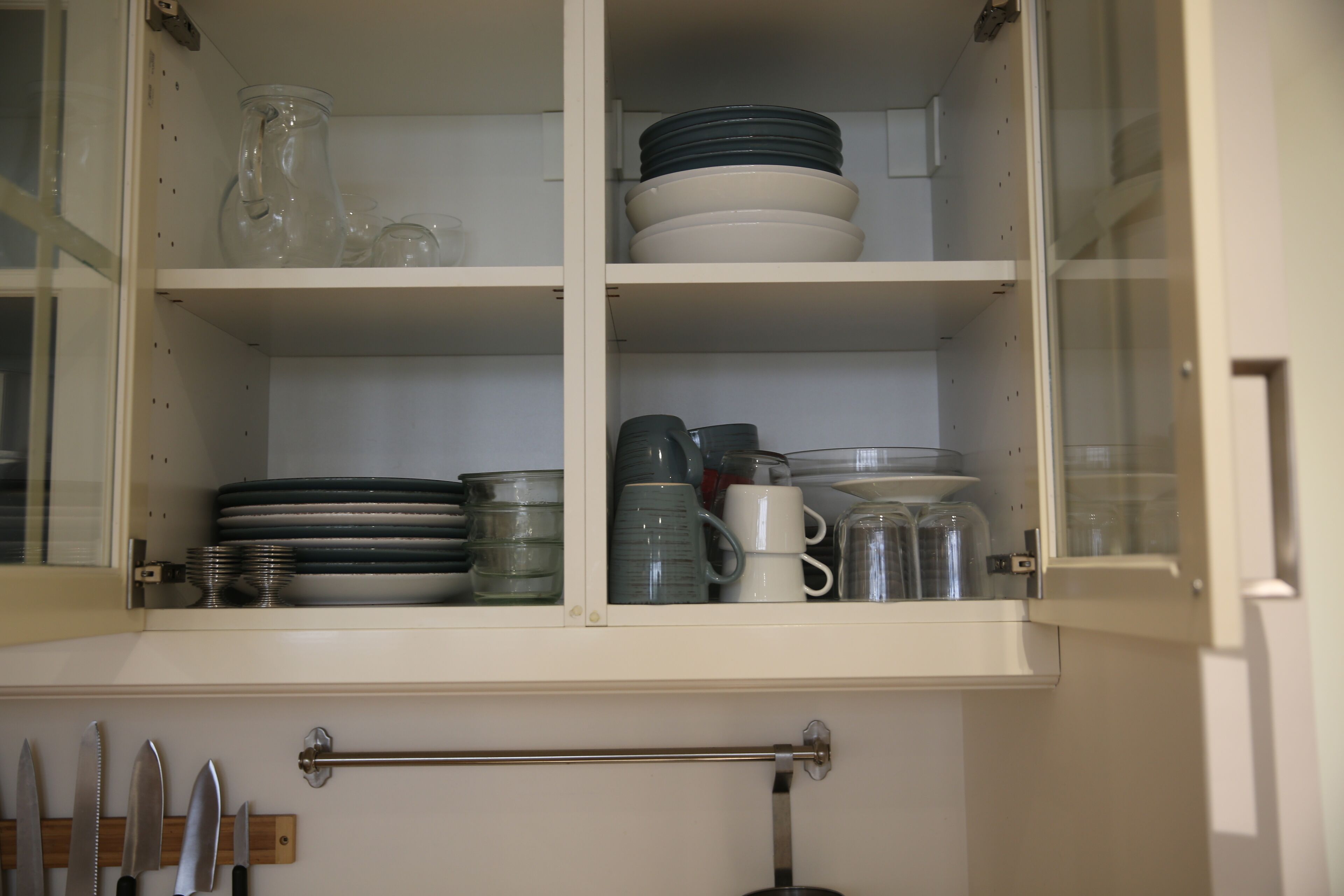 A kitchen cabinet with shelves holding various dishes and utensils.