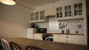 A kitchen with white cabinets, a wooden dining table, and a microwave.
