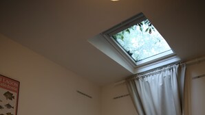 A hotel room with a bed, a window with curtains, and a poster on the wall.
