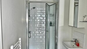 Une salle de bain moderne avec une douche à parois de verre, un lavabo blanc et un miroir au-dessus du lavabo.