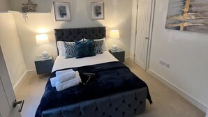 Une chambre à coucher avec un grand lit, deux tables de chevet, une décoration en forme d’étoile, des tableaux encadrés, une lampe et un tableau accroché au mur.