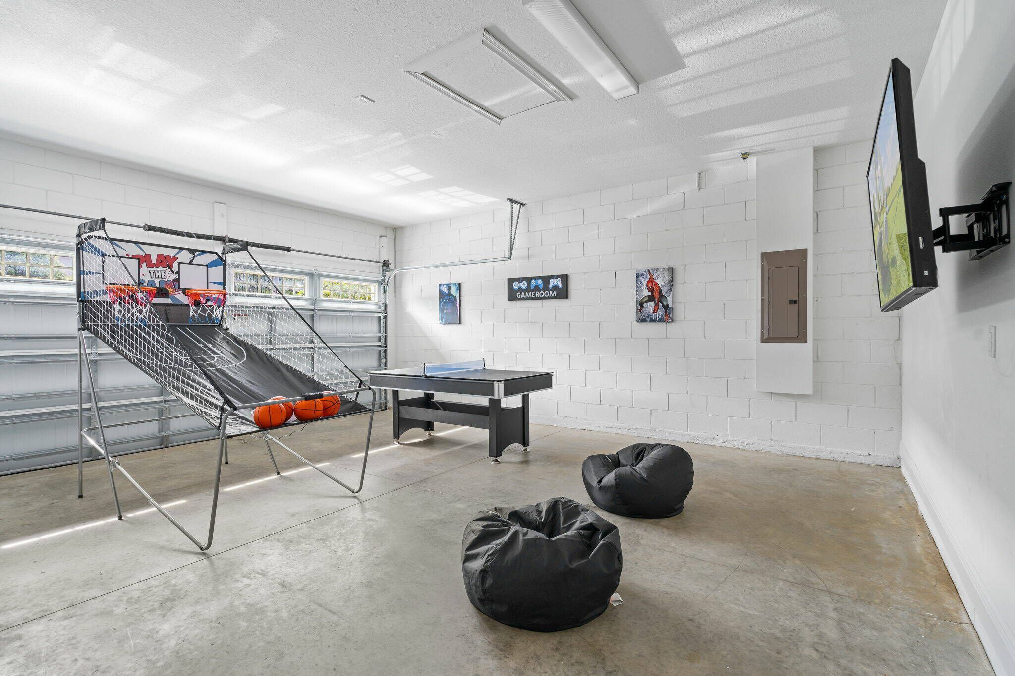 Een moderne kamer met een tafeltennistafel, zitzakken en een basketbalring.