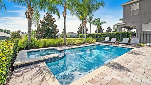 A swimming pool with a hot tub, surrounded by palm trees and a brick patio. - Games Room/Private Pool and Hot Tub/Beautifully furnished/Movie Room/Free Wifi (Kissimmee)