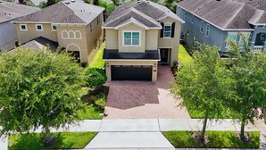 A residential area with houses featuring pitched roofs and a central driveway leading to a garage. - Games Room/Private Pool and Hot Tub/Beautifully furnished/Movie Room/Free Wifi (Kissimmee)