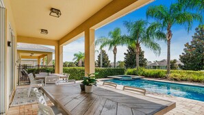 An outdoor patio with a pool, surrounded by palm trees and a well-maintained hedge. - Games Room/Private Pool and Hot Tub/Beautifully furnished/Movie Room/Free Wifi (Kissimmee)