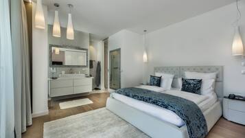 Un dormitorio moderno con una cama grande, un tocador con espejo y luces colgantes.