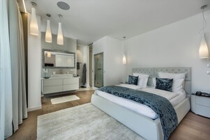 Un dormitorio moderno con una cama grande, un tocador con espejo y luces colgantes.