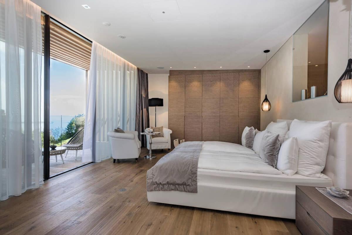 Une chambre moderne avec un grand lit, un petit coin salon et une vue sur l’extérieur.