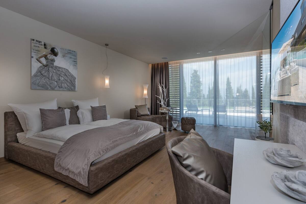 Une chambre d’hôtel moderne, dotée d’un grand lit, d’un bureau et offrant une vue sur l’extérieur.