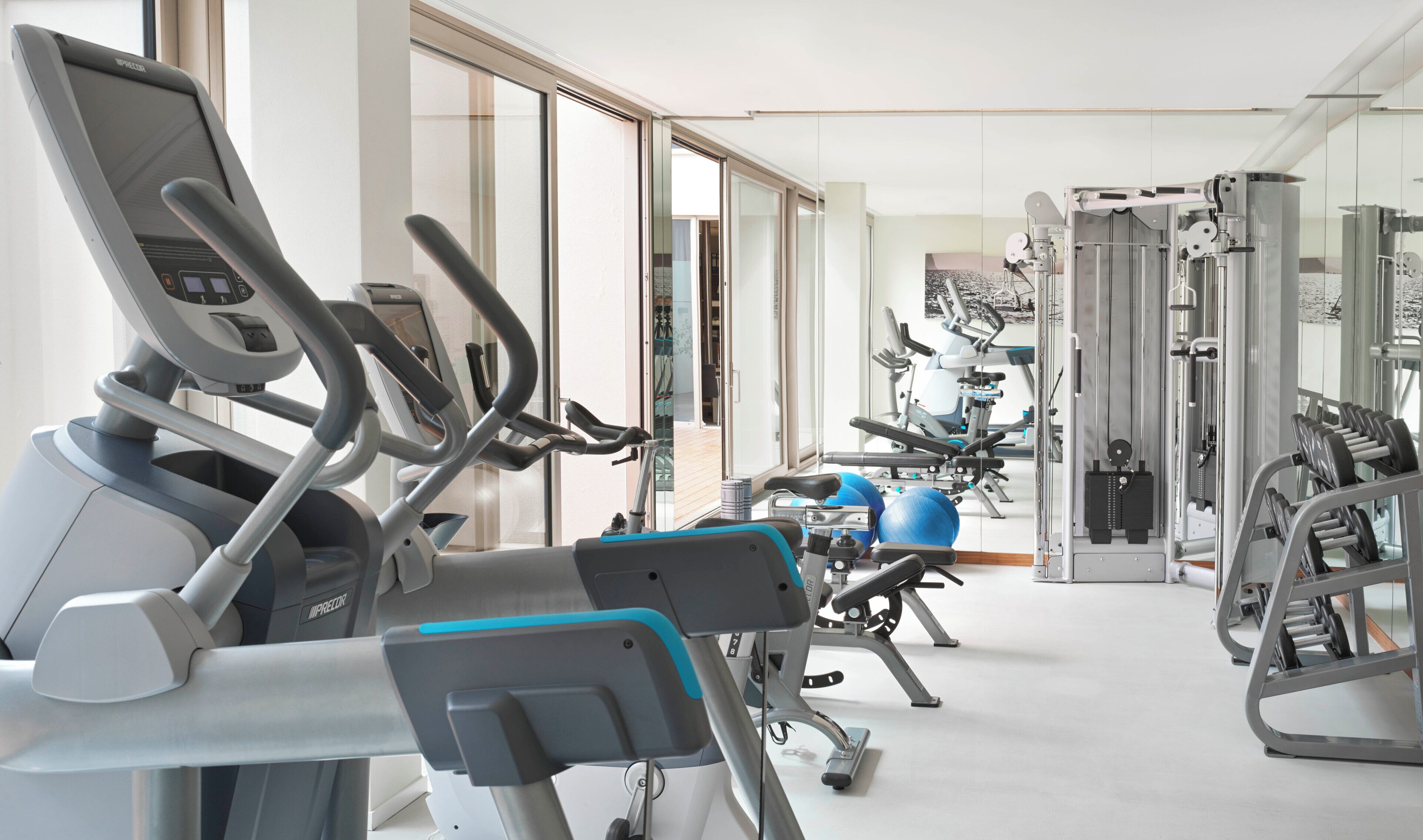 Ein Fitnessstudio mit verschiedenen Trainingsgeräten, darunter Laufbänder, Kraftgeräte und Trainingsbälle.