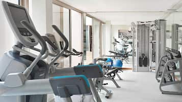 Ein Fitnessstudio mit verschiedenen Trainingsgeräten, darunter Laufbänder, Kraftgeräte und Trainingsbälle.