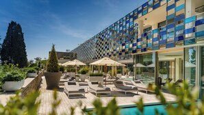 Et moderne hotel med poolområde, liggestole og plantekasser.