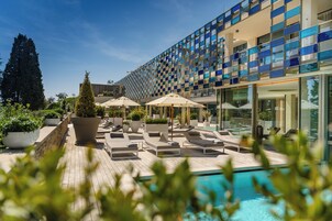Una piscina techada, una piscina al aire libre, sombrillas