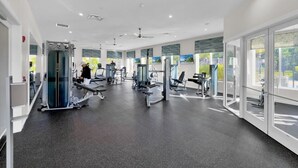 Een moderne sportschool met diverse fitnessapparaten, grote ramen en een ruim, schoon interieur.