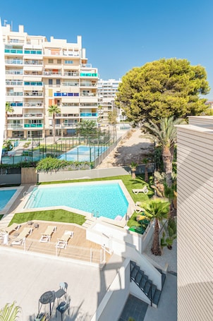 Una piscina al aire libre, sombrillas, sillones reclinables de piscina