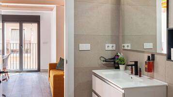 Een moderne badkamer met een grote spiegel, een wit wastafelmeubel en een plant in pot.