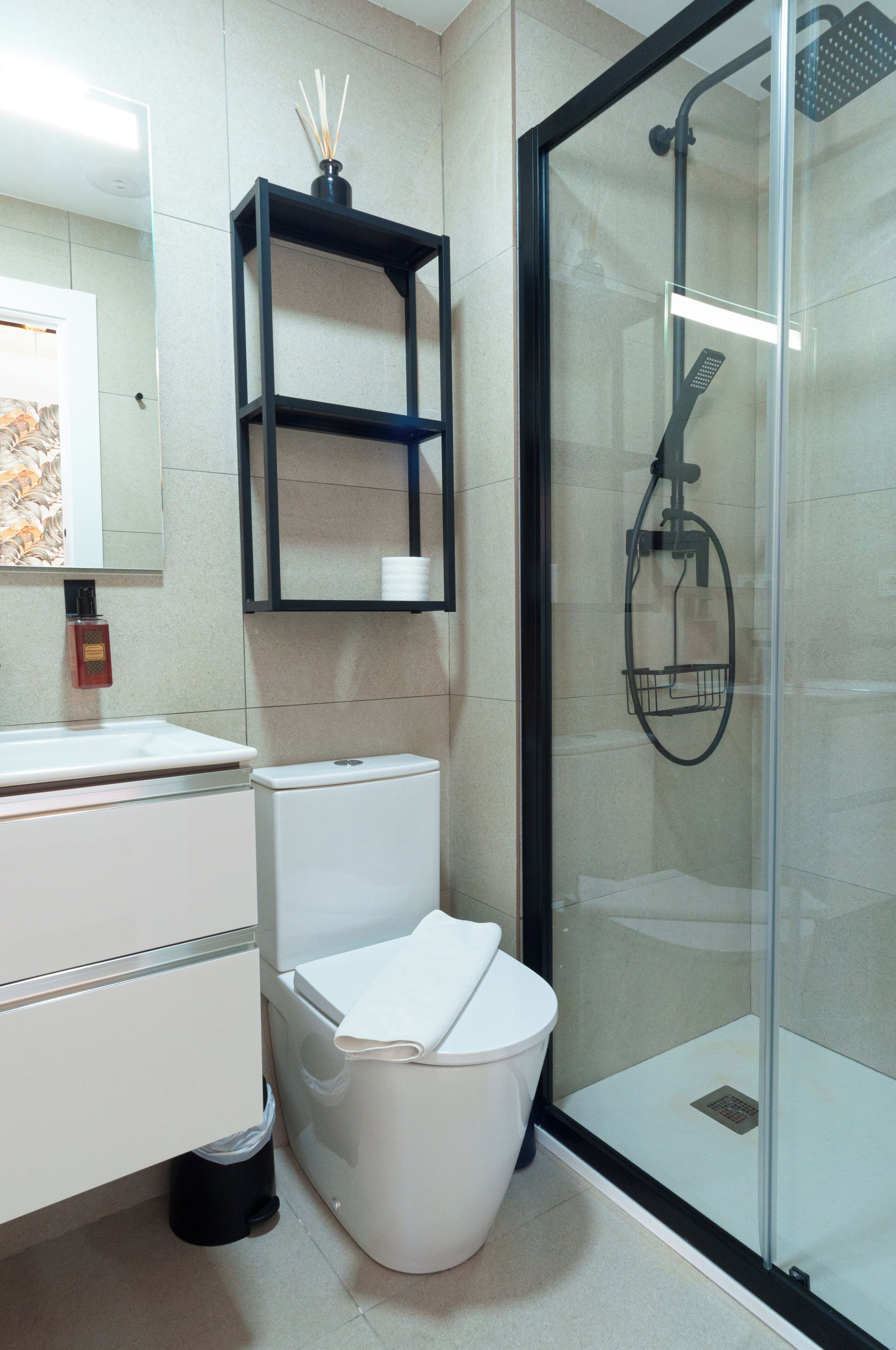 A modern bathroom with a toilet, sink, and glass shower enclosure.