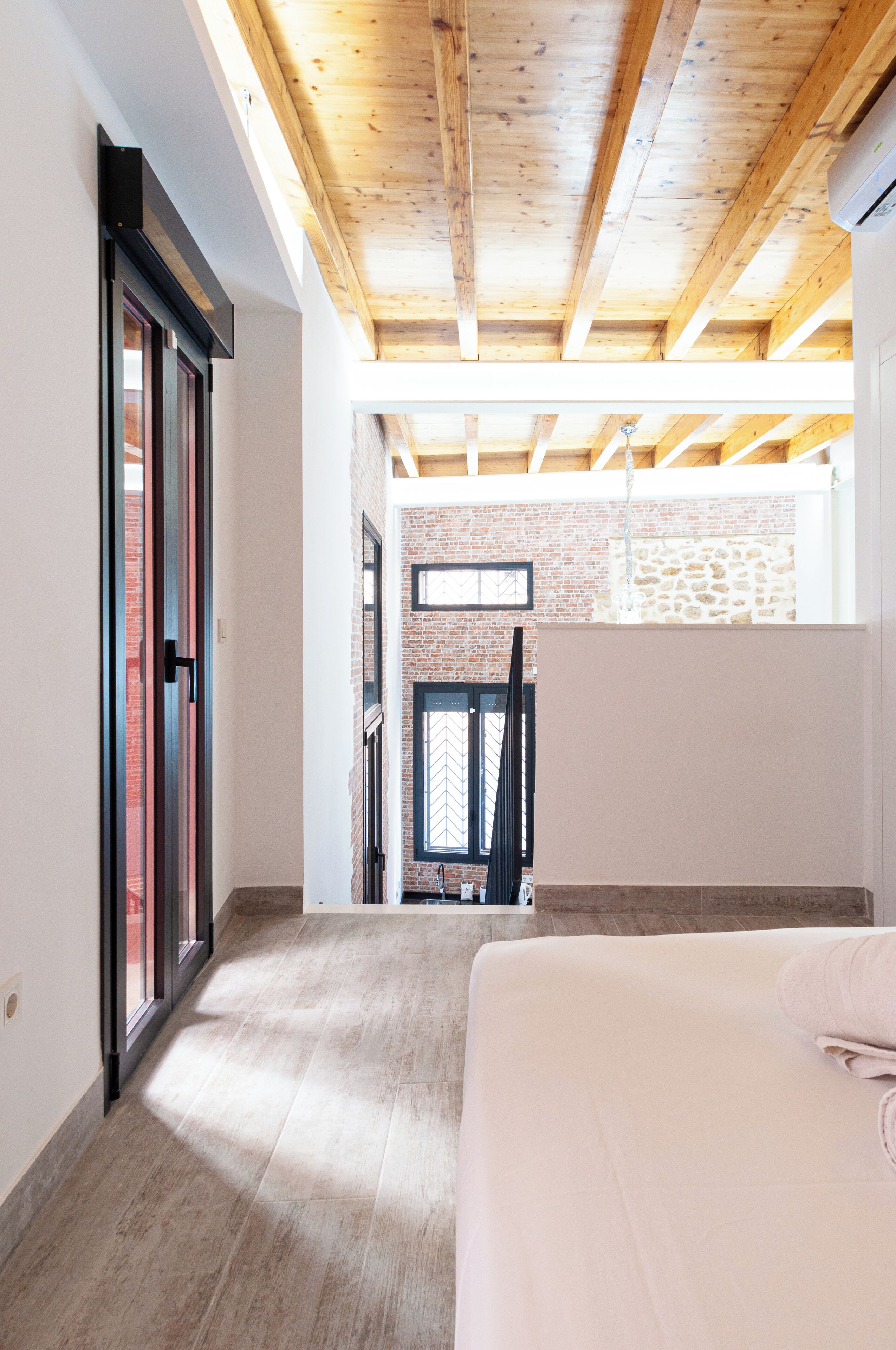 A spacious room with a high ceiling, large windows, and a view of a brick building.