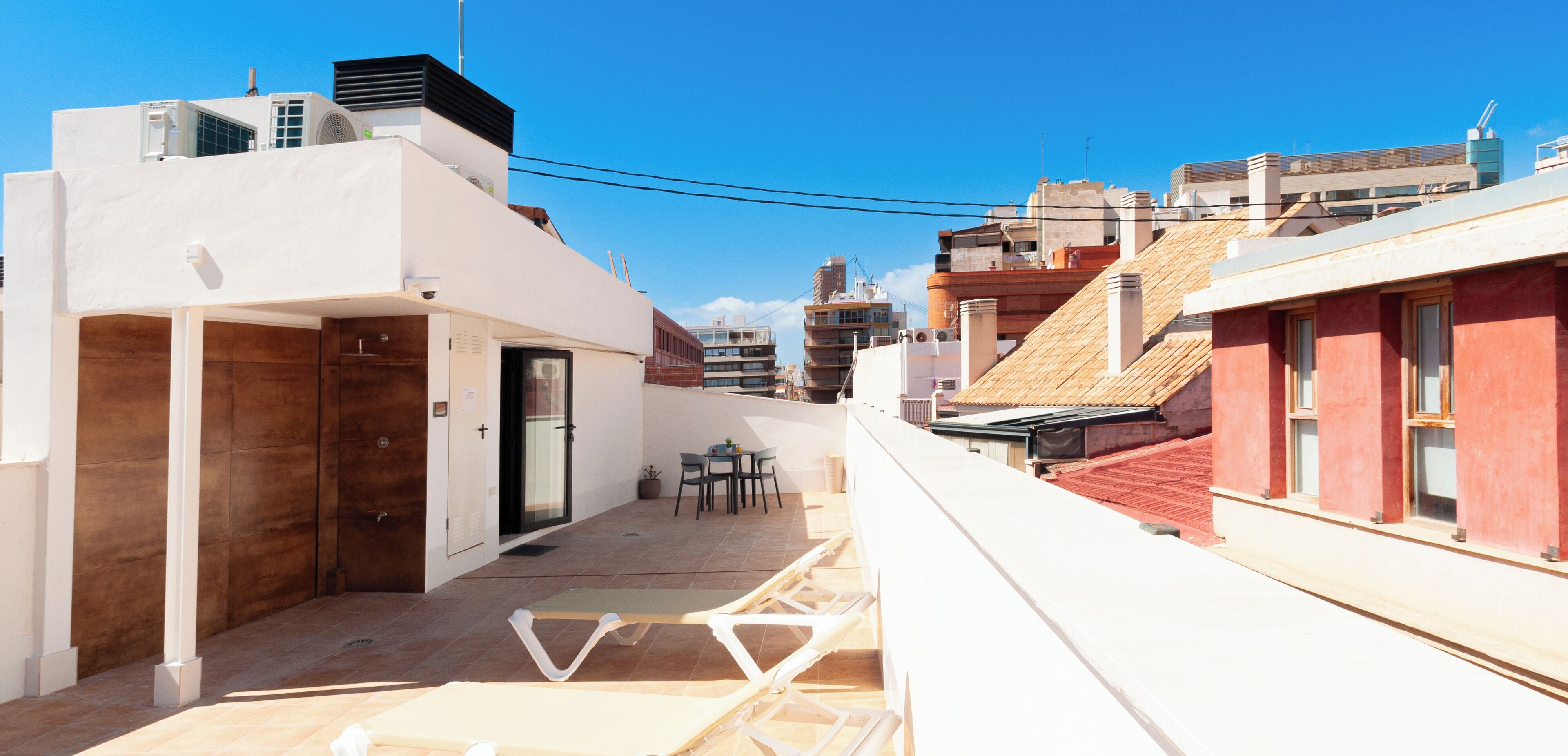 A rooftop terrace with a small seating area, a door, and a window.