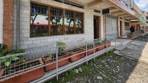 A building with a brick facade, large windows, and a metal fence with potted plants. - KENLANDS RELAX INN (Nakuru)