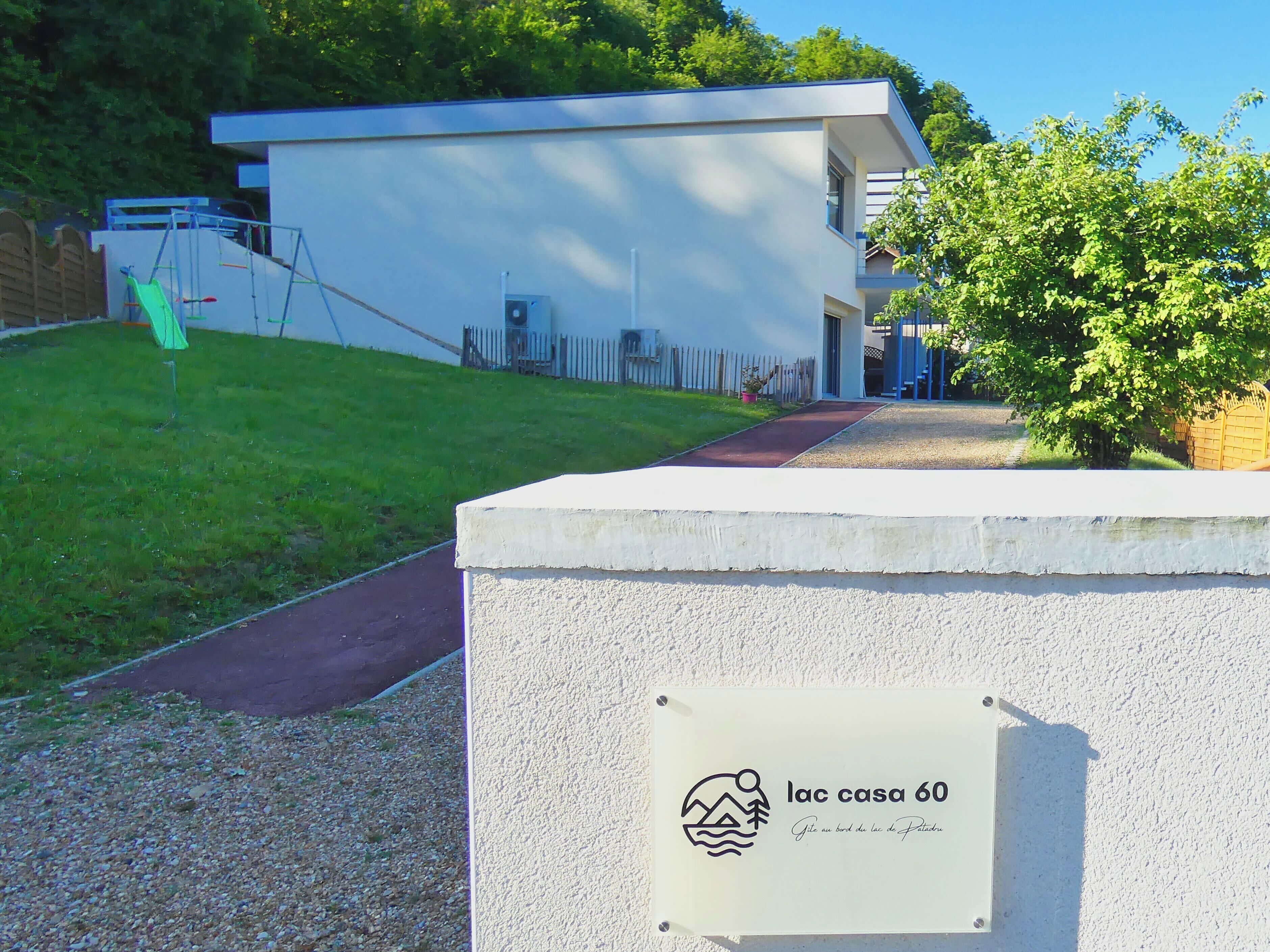 Ein modernes Gebäude mit einem Schild, auf dem 'lac casa 60' steht, und ein kleiner Baum davor.
