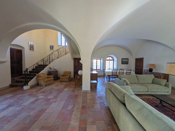 A spacious living area with a staircase, a dining table, and two sofas.