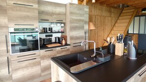 Una cocina moderna con armarios de madera, encimera negra y horno empotrado.