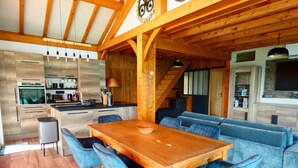 Una cocina moderna con armarios de madera, horno integrado y comedor con mesa de madera y sillas tapizadas en azul.