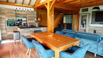 Une cuisine moderne avec des meubles en bois, un four encastré et un coin repas comprenant une table en bois et des chaises à revêtement bleu.