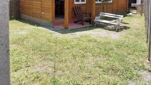 Puuinen mökki, jossa on kuisti, penkki ja pieni puutarha-alue.