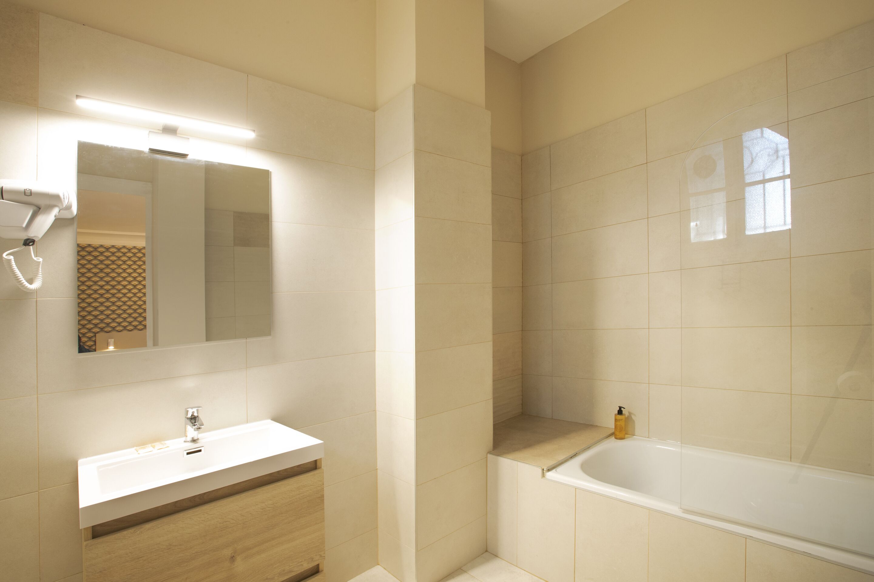 Une salle de bain moderne avec un lavabo blanc, un miroir et une baignoire.