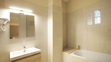 Une salle de bain moderne avec un lavabo blanc, un miroir et une baignoire.