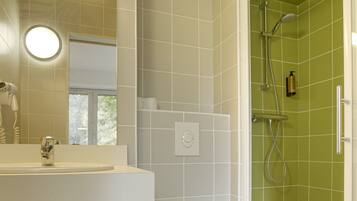A modern bathroom with a white sink, a toilet, and a shower area with green tiles.