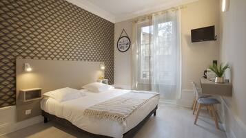 Relax in a stylish room with a large bed, wall-mounted TV, and desk area.