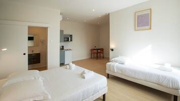 A hotel room with two beds, a desk, a chair, a microwave, and a framed artwork on the wall.