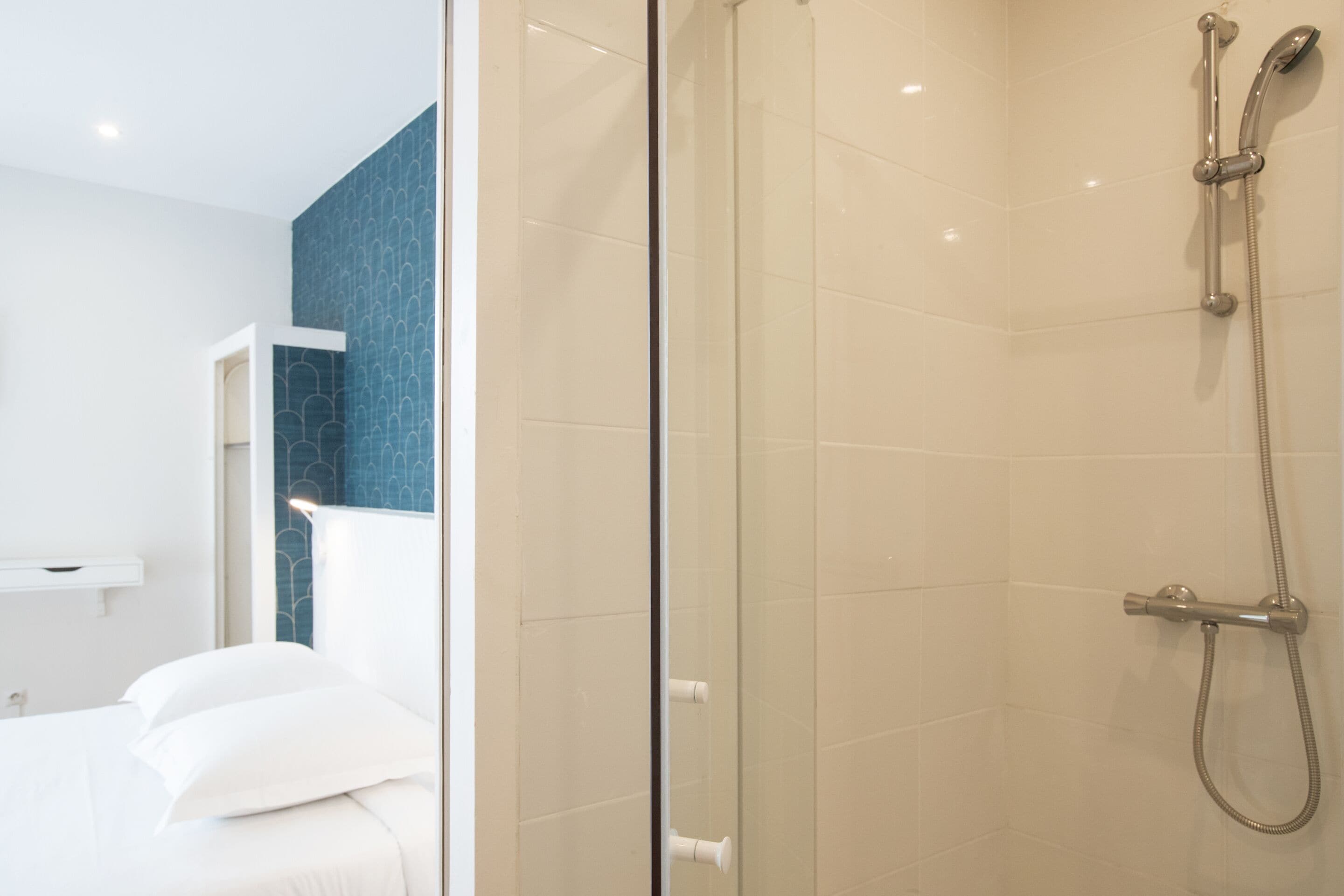 Une salle de bain moderne avec une douche à l’italienne en verre, une baignoire blanche et un mur d’accent bleu.