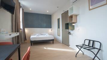 Ett modernt hotellrum med en säng, ett skrivbord, en stol och ett litet bord.