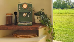 A kitchenette with a vintage coffee maker, a wooden cabinet, and a view of a green field through an open door. - Horizon - L'évasion Autonome (Cysoing)