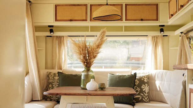 A cozy seating area with a table, a vase with dried plants, and a window with curtains. - Horizon - L'évasion Autonome (Cysoing)