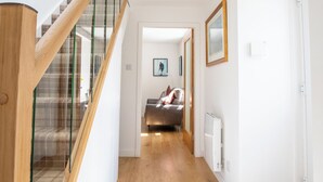 A modern interior with a wooden staircase, a hallway leading to a bedroom, and a view of the outdoors. - A charming cottage in the heart of Ballater, with a beautiful & modern interior (Ballater)