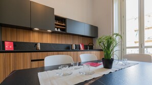 Una cocina moderna con armarios oscuros, encimera de madera y una mesa de comedor con vasos y una planta en maceta.