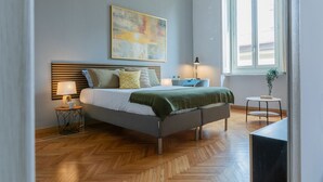 Un dormitorio moderno con cama, mesitas de noche, una ventana y un cuadro en la pared.