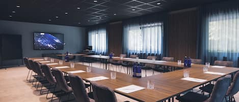 A conference room with a long table, chairs, and a television screen displaying a cityscape.