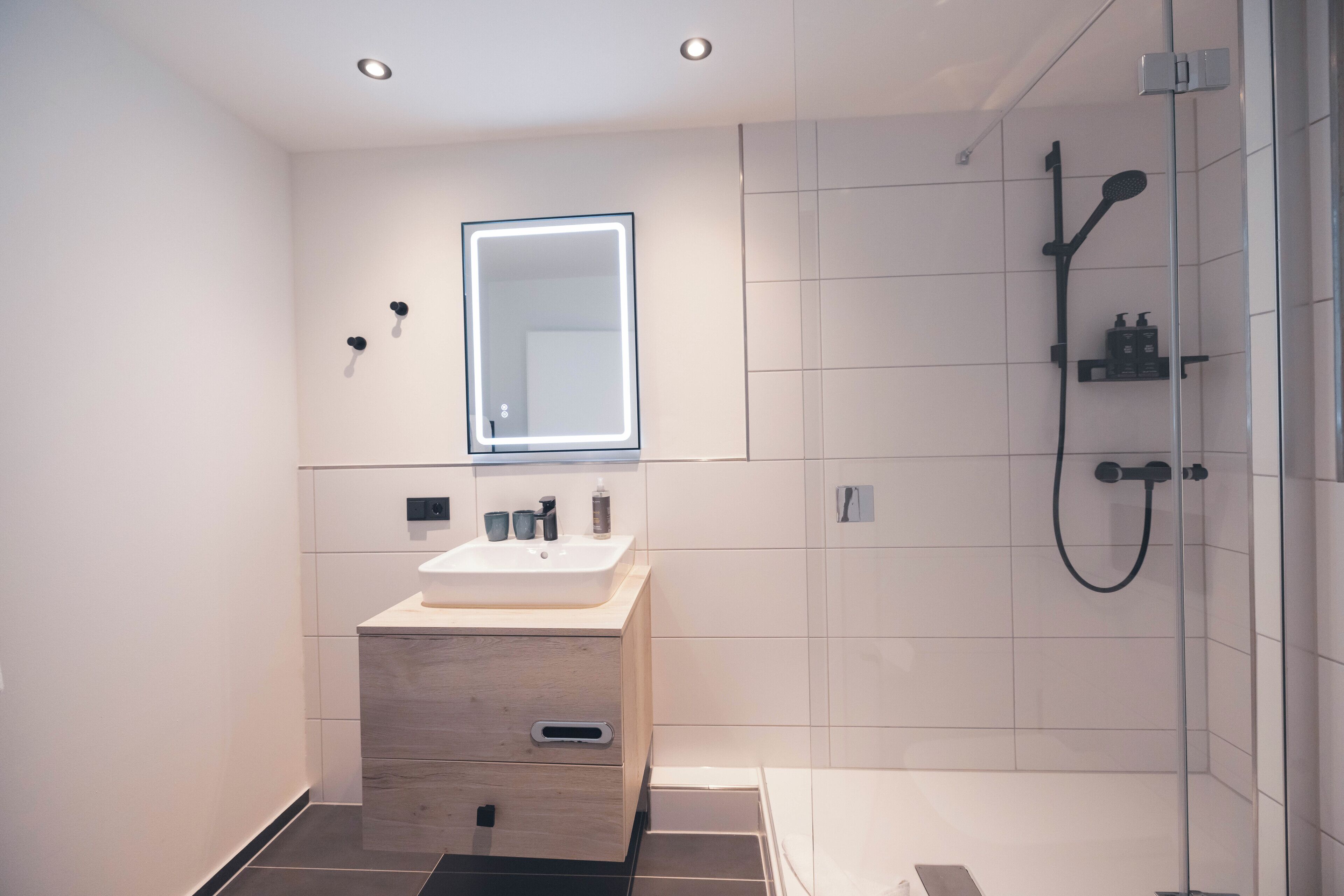 A modern bathroom with a vanity, mirror, and shower.